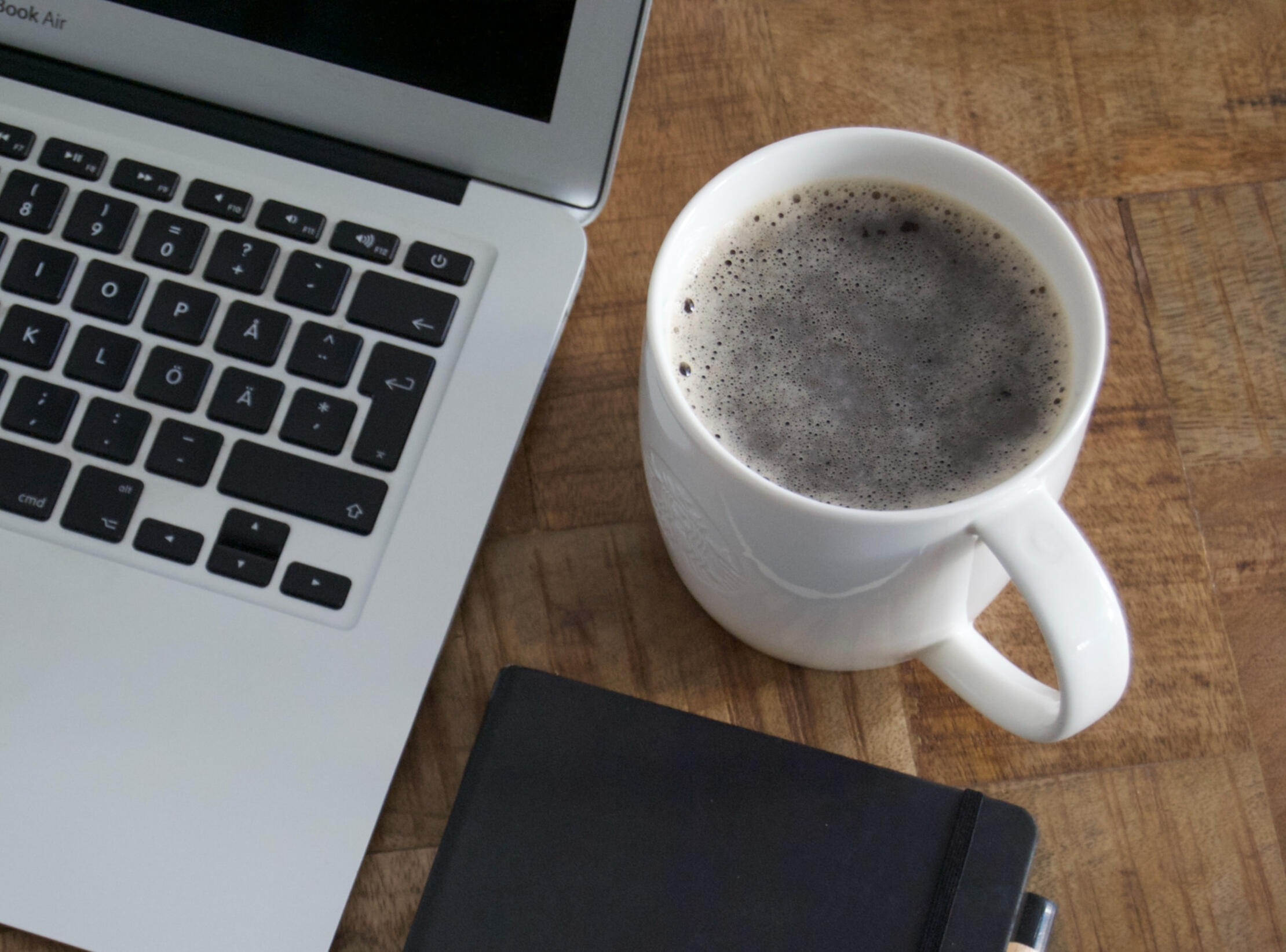 The job seekers desktop, there is coffee, a laptop, and a notebook